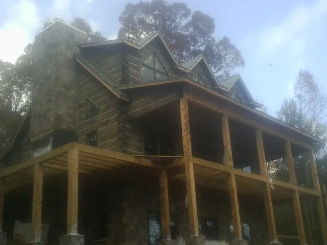 Stone chimney and dormers on a large log home with a timber porch in Deer Park